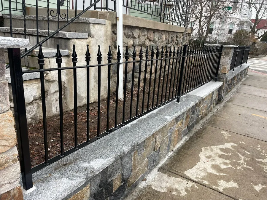 Black iron picket fence on a granite wall